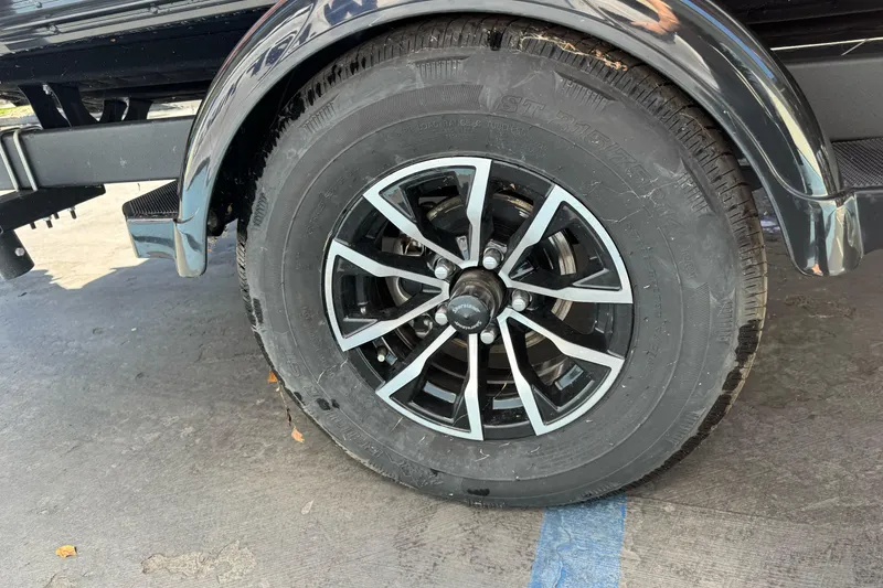 Slide: The Image of 2026 Lund 1775 Crossover XS trailer wheel with black and silver alloy design. - 3