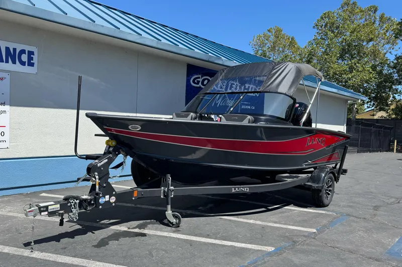 Slide: The Image of 2026 Lund 1775 Crossover XS boat on trailer, parked outside a building. - 1