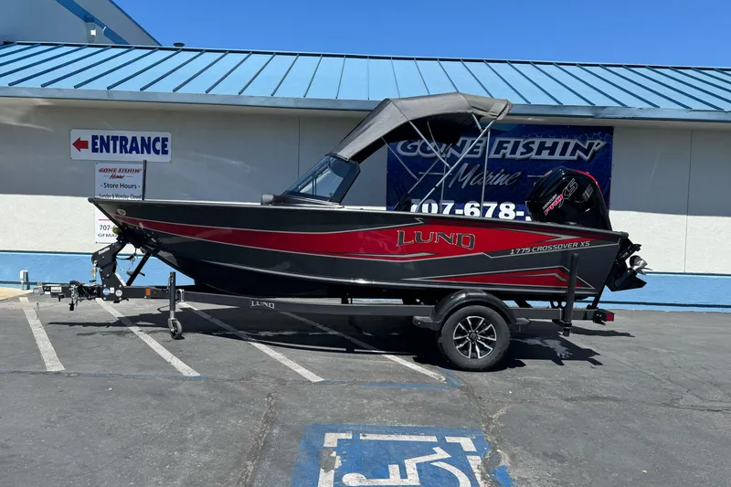 The Image of 2026 Lund 1775 Crossover XS boat on trailer outside marine store. - 0