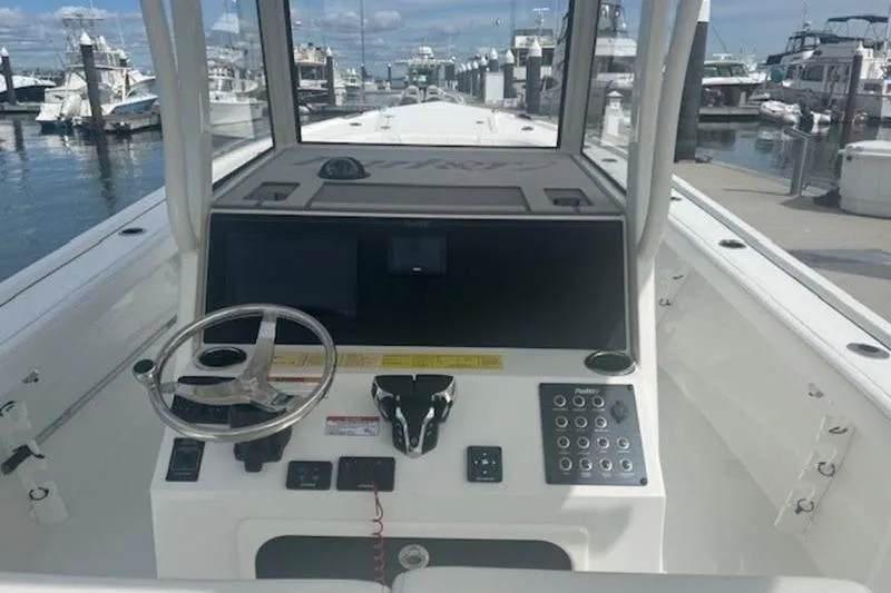 Slide: The Image of 2025 Parker 2900 Center Console boat dashboard at marina, featuring steering wheel and control panel. - 13