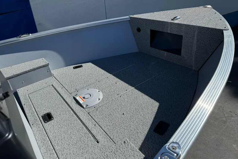 Slide: The Image of 2026 Lund 1600 Fury SS boat interior with gray carpeted deck and storage compartments. - 7