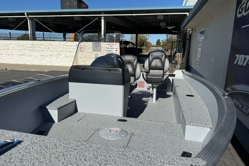 Slide: The Image of 2026 Lund 1600 Fury SS boat interior with seating and console, parked outdoors. - 8