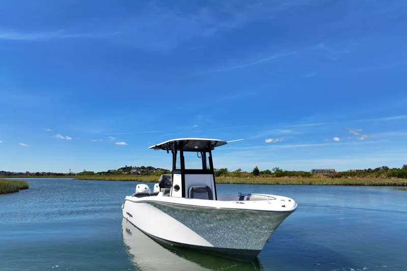 Slide: The Image of 2026 NauticStar 252 Legacy boat on calm water under clear blue sky. - 11