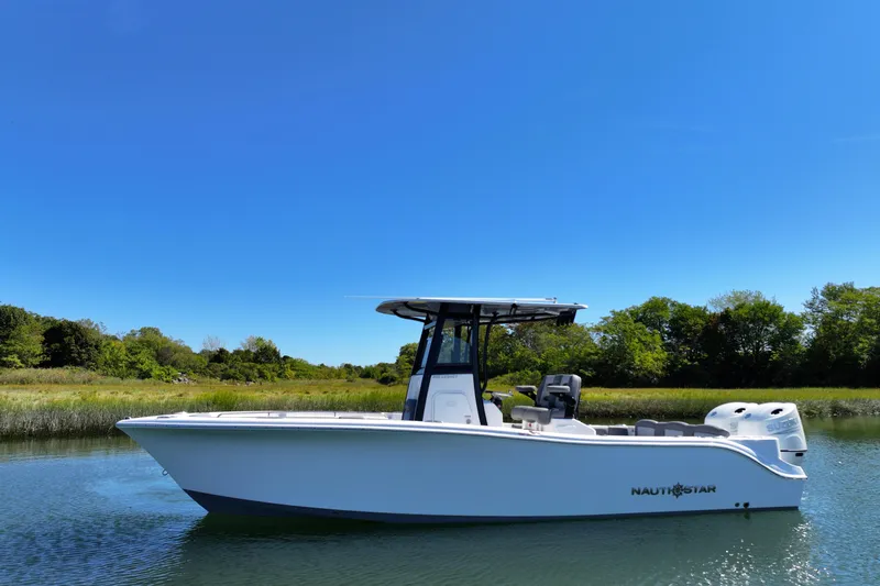 Slide: The Image of 2026 NauticStar 252 Legacy boat on calm water under clear blue sky. - 15