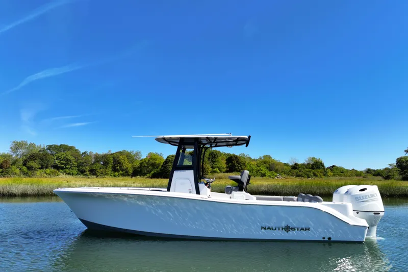 Slide: The Image of 2026 NauticStar 252 Legacy boat on calm water under clear blue sky. - 16