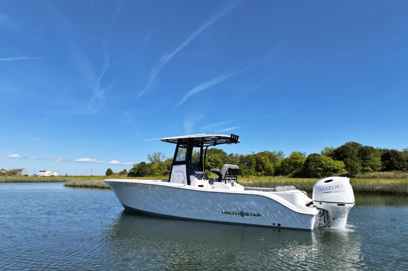 Slide: The Image of 2026 NauticStar 252 Legacy boat on calm water under clear blue sky. - 17