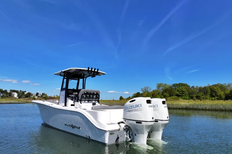 Slide: The Image of 2026 NauticStar 252 Legacy boat with dual Suzuki engines on a serene lake. - 18