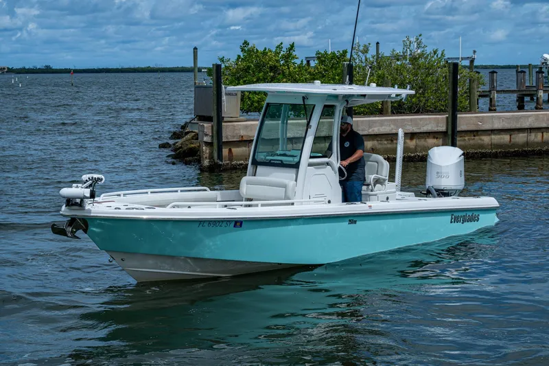 Slide: The Image of 2021 Everglades 253 Center Console boat on water near dock, under cloudy sky. - 4
