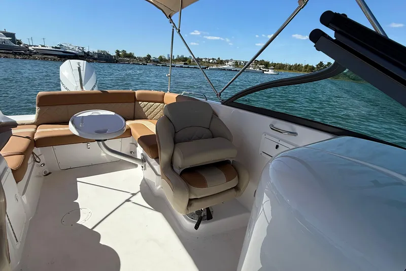 Slide: The Image of 2025 NauticStar 243 DC Deck boat interior with seating and table on the water. - 12