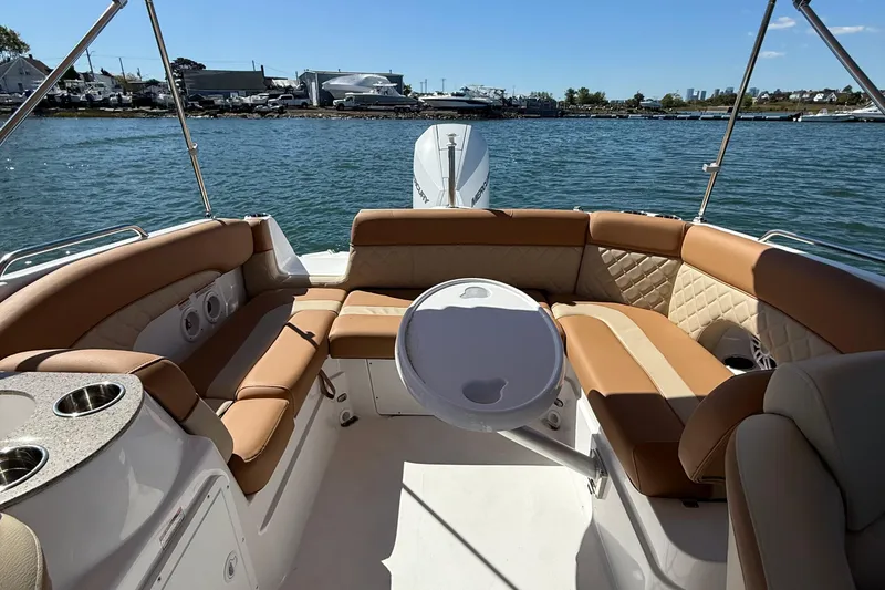 Slide: The Image of 2025 NauticStar 243 DC Deck boat interior with tan seating and table on the water. - 13