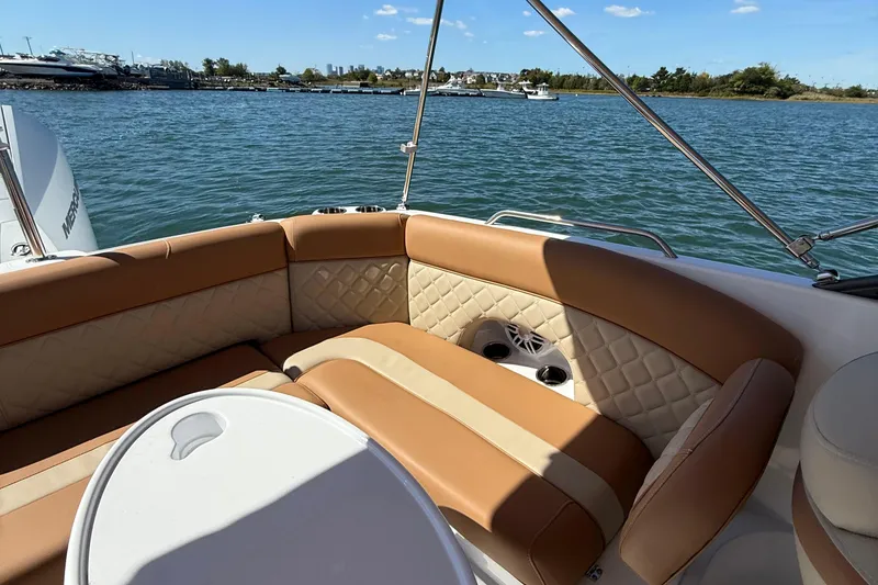 Slide: The Image of 2025 NauticStar 243 DC Deck boat interior with tan seating, on a sunny day. - 16