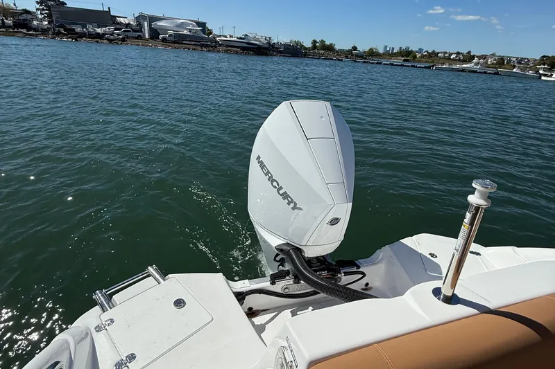 Slide: The Image of 2025 NauticStar 243 DC Deck boat with Mercury outboard engine on calm water. - 17