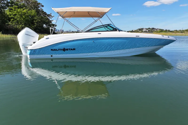 Slide: The Image of 2025 NauticStar 243 DC Deck boat with canopy on calm water. - 3
