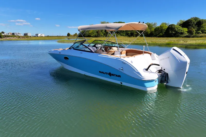 Slide: The Image of 2025 NauticStar 243 DC Deck boat on calm water, featuring a sleek design and powerful outboard motor. - 4