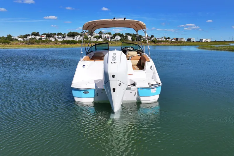 Slide: The Image of 2025 NauticStar 243 DC Deck boat on calm water, sunny day, scenic background. - 6