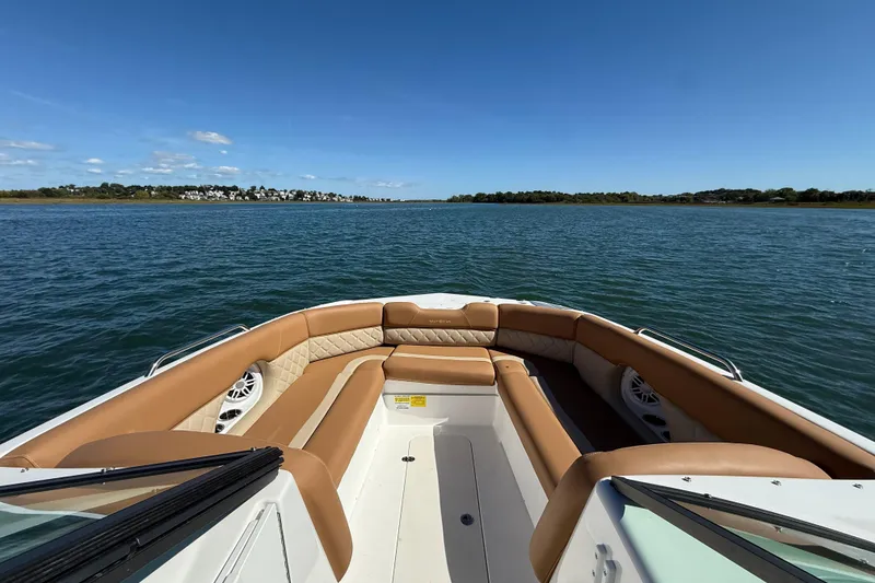 Slide: The Image of 2025 NauticStar 243 DC Deck boat interior with tan seating on calm water. - 8