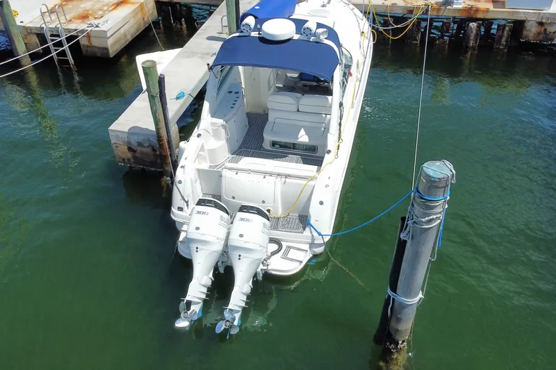 Slide: The Image of 2005 Monterey 302 Cruiser docked with twin outboard engines, blue canopy, and spacious deck. - 33