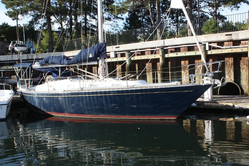 The Image of 1976 Tartan 38 sailboat docked in a marina, surrounded by trees and calm water. - 0