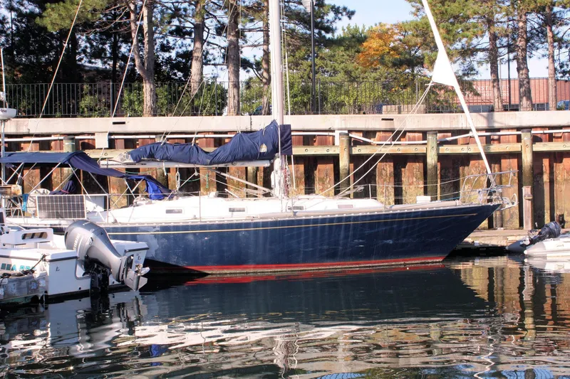 Slide: The Image of 1976 Tartan 38 sailboat docked at a marina, surrounded by trees and calm water. - 2