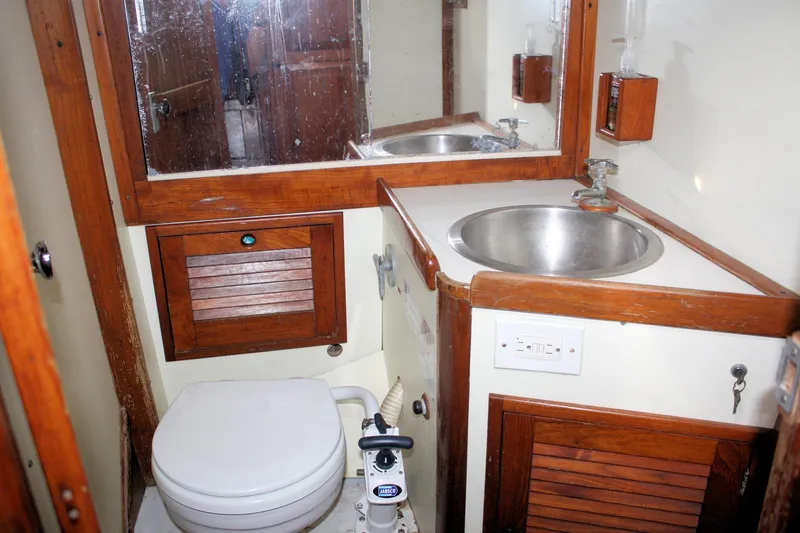 Slide: The Image of 1976 Tartan 38 yacht bathroom with wooden accents, sink, and marine toilet. - 20