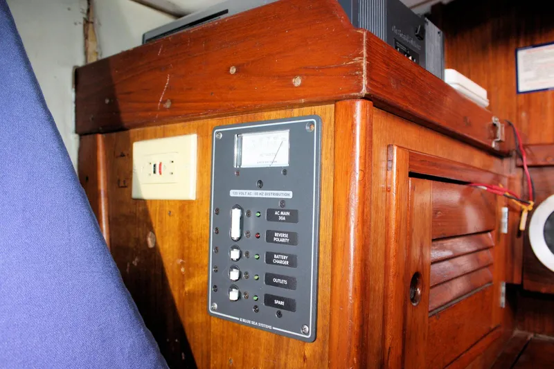 Slide: The Image of Electrical panel inside a 1976 Tartan 38 sailboat, featuring wooden cabinetry and control switches. - 50