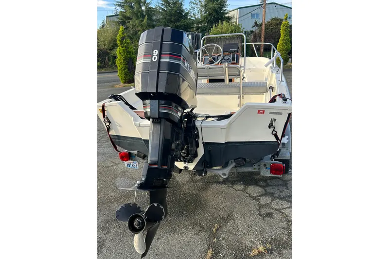 Slide: The Image of 1990 Wahoo 16.2 Striper boat with outboard motor, parked on a trailer. - 11