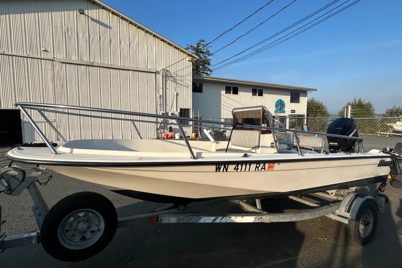 Slide: The Image of 1990 Wahoo 16.2 Striper boat on trailer, parked near a building. - 2