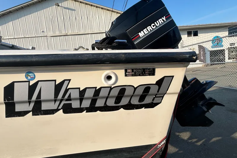 Slide: The Image of 1990 Wahoo 16.2 Striper boat with Mercury engine, docked near a warehouse. - 3