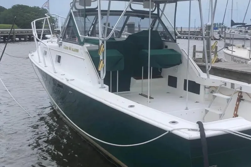 Slide: The Image of 1987 Luhrs 30 Alura Classic boat docked, featuring green accents and spacious deck. - 3