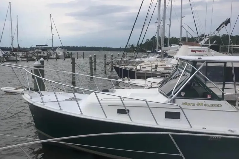 Slide: The Image of 1987 Luhrs 30 Alura Classic boat docked at a marina, surrounded by other vessels. - 37