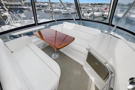 Slide: The Image of Luxurious interior of 2008 Sea Ray 47 Sedan Bridge yacht with white seating and wooden table. - 17