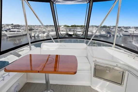 Slide: The Image of 2008 Sea Ray 47 Sedan Bridge interior with wooden table and marina view. - 20
