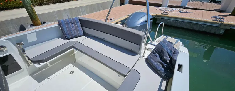 Slide: The Image of 2019 Jeanneau Leader 7.5 CC boat interior with cushioned seating and pillows at dock. - 5