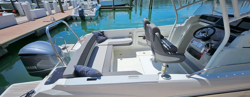 Slide: The Image of 2019 Jeanneau Leader 7.5 CC boat interior with seating and steering wheel at marina. - 7