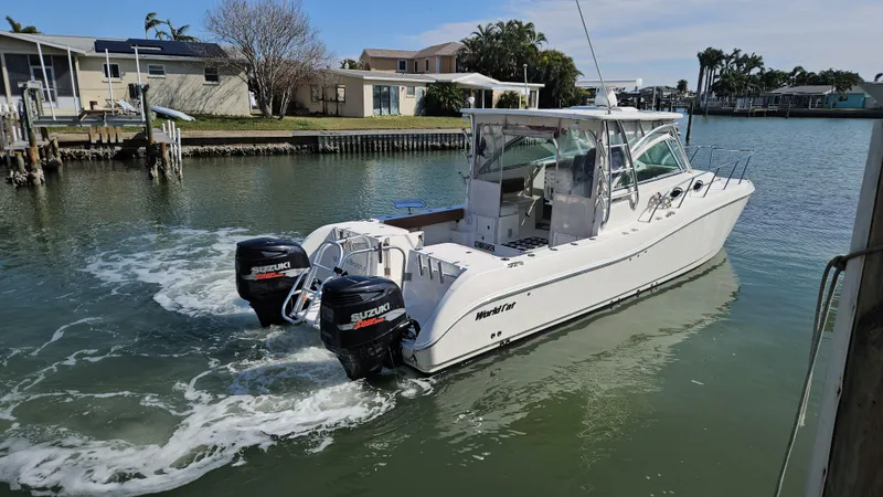 Slide: The Image of 2008 World Cat 320 EC boat with twin Suzuki outboard engines on a calm waterway. - 14