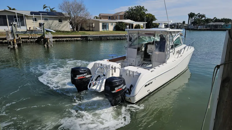 Slide: The Image of 2008 World Cat 320 EC boat with dual Suzuki engines in a calm marina setting. - 16