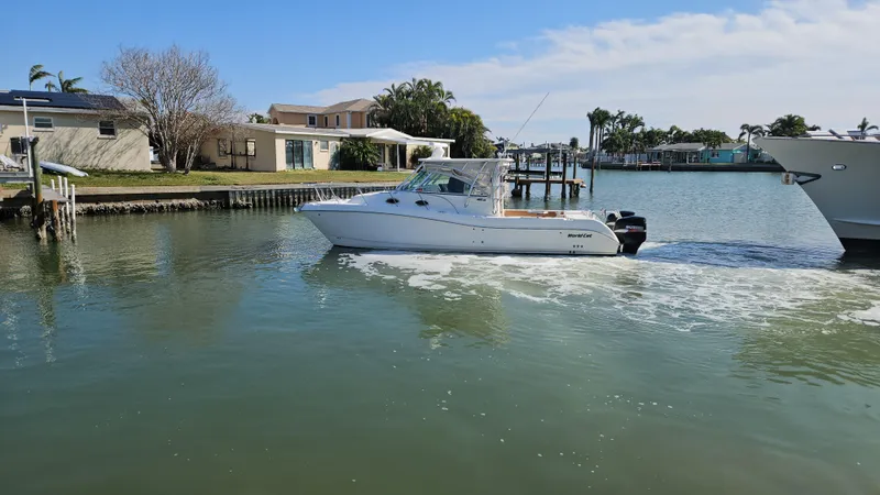 Slide: The Image of 2008 World Cat 320 EC boat cruising in a calm residential waterway. - 2