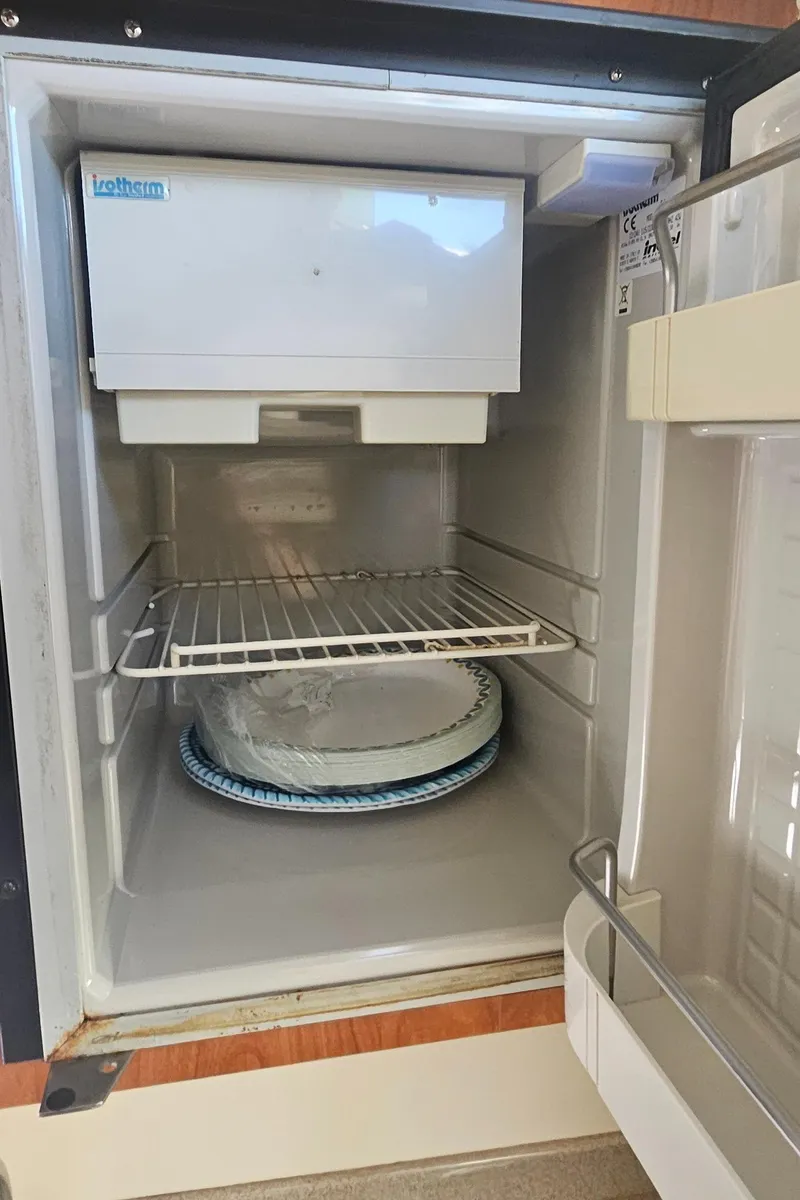 Slide: The Image of Open refrigerator inside a 2008 World Cat 320 EC boat, featuring a wire shelf and ice maker. - 27