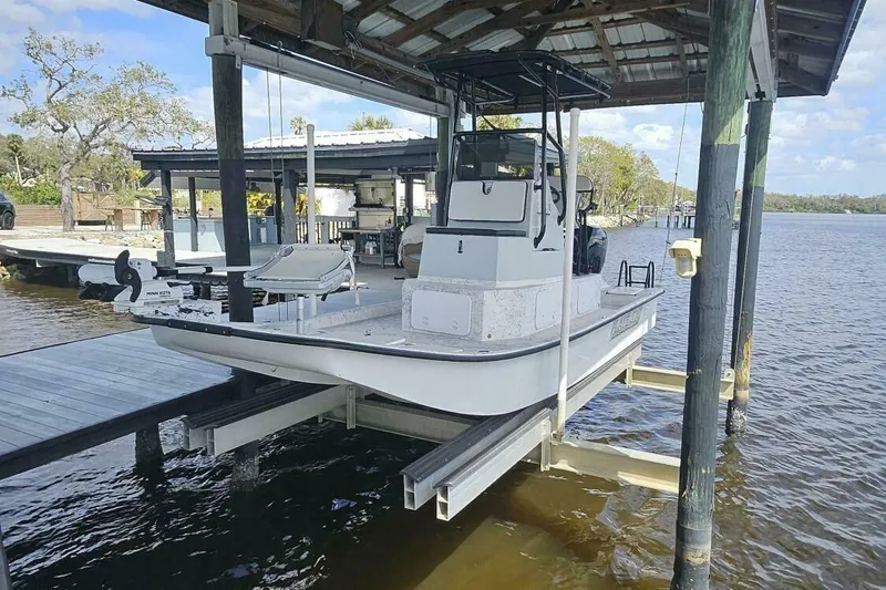The Image of 2021 Flats Cat 21' boat docked under a covered pier on a sunny day. - 1