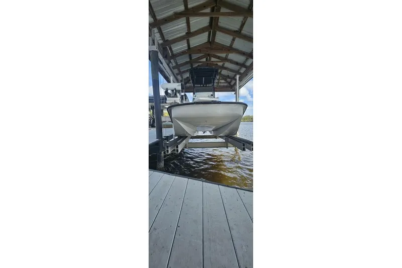 Slide: The Image of 2021 Flats Cat 21' boat on lift under dock roof, water view. - 4