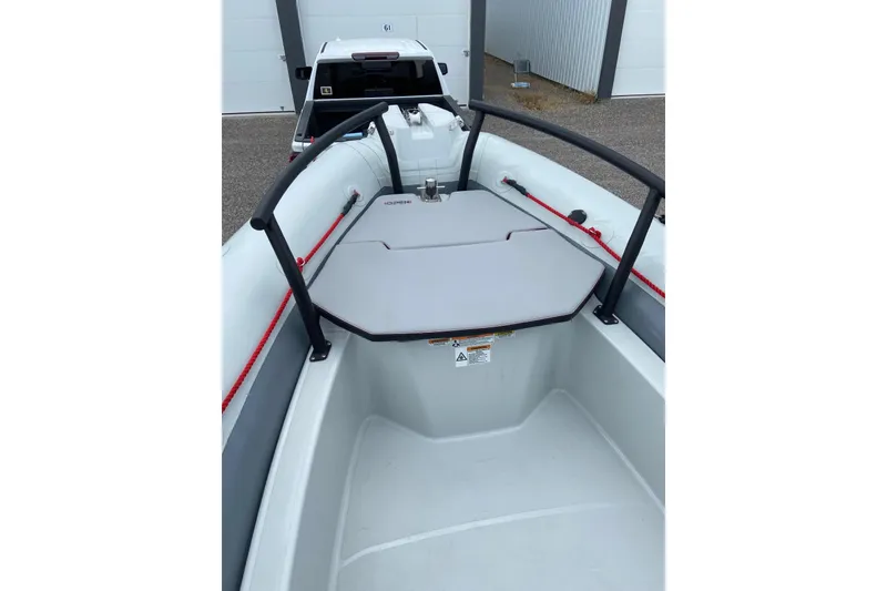 Slide: The Image of 2023 Zodiac Pro Open boat interior with seating and railing, parked near a white vehicle. - 11
