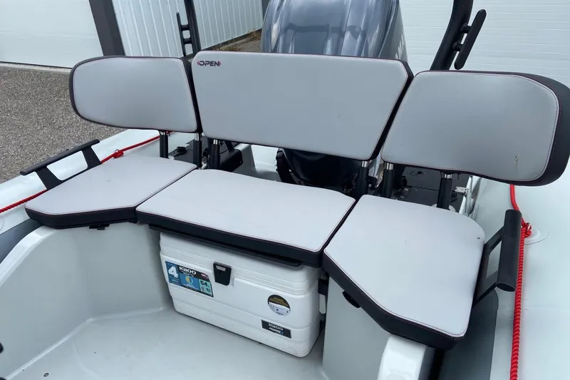 Slide: The Image of 2023 Zodiac Pro Open boat seating area with cooler and engine in background. - 8