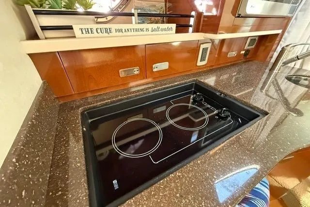 Slide: The Image of Modern kitchen in 2012 Sea Ray 330 Sundancer yacht with sleek cooktop and wooden cabinetry. - 19