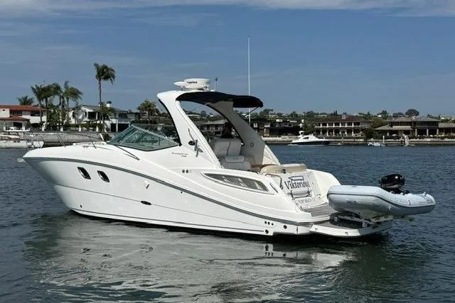 Slide: The Image of 2012 Sea Ray 330 Sundancer yacht on calm water, with coastal homes in the background. - 3