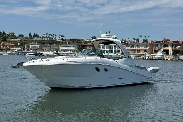 Slide: The Image of 2012 Sea Ray 330 Sundancer yacht on calm water, with coastal homes in the background. - 5