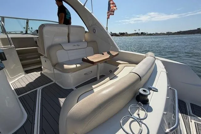 Slide: The Image of 2012 Sea Ray 330 Sundancer boat interior with seating and table on a sunny day. - 9
