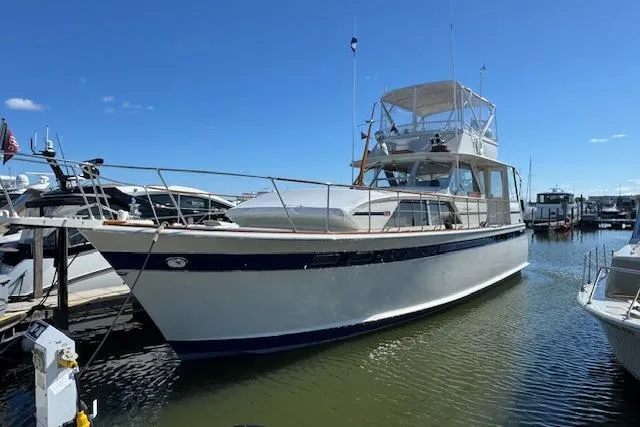The Image of 1974 Chris-Craft 47 Commander yacht docked in a marina under clear blue skies. - 0