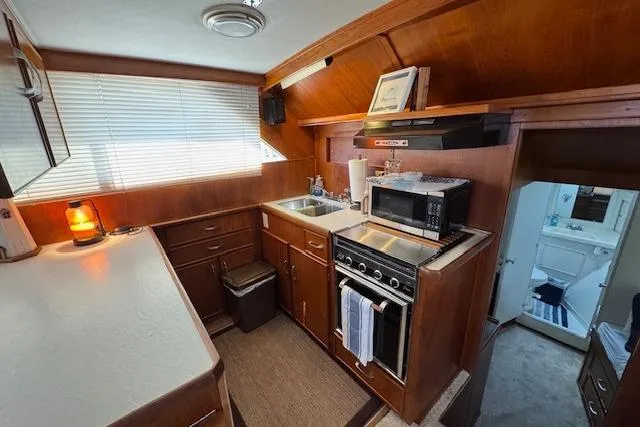 Slide: The Image of 1974 Chris-Craft 47 Commander yacht kitchen with wood cabinetry, stove, and microwave. - 27