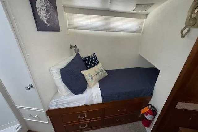 Slide: The Image of 1974 Chris-Craft 47 Commander cabin with cozy bed, nautical decor, and wooden storage drawers. - 43