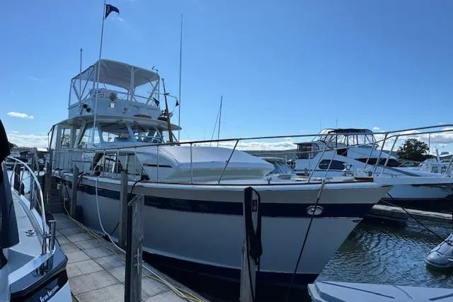 Slide: The Image of 1974 Chris-Craft 47 Commander yacht docked at a marina under a clear blue sky. - 5